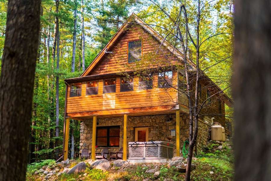 Pine Cabin — zewnętrze domku z jacuzzi na tarasie, otoczone lasem